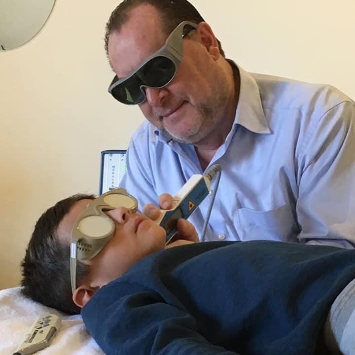 Raf Verwasch behandelt een kind met laseracupunctuur bij Mediraf in Beek